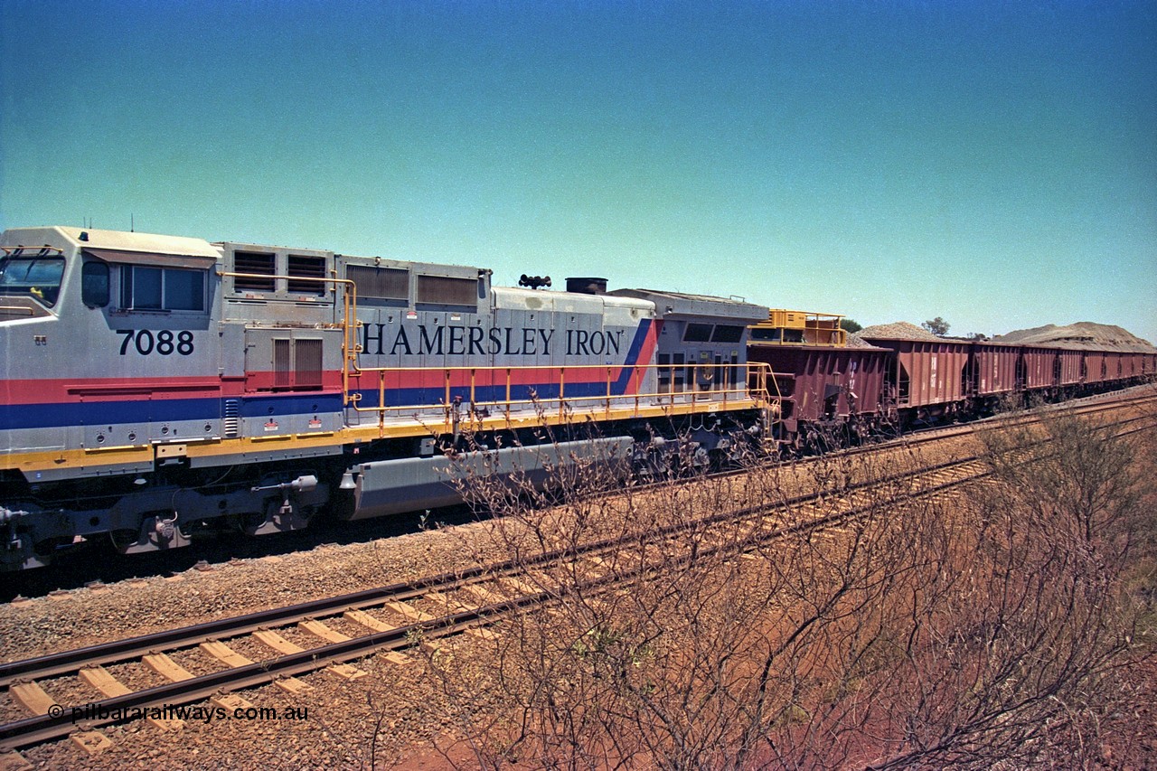 252-09
Cockatoo Siding 273 km on the Hamersley Iron line to Yandi, General Electric built 9-44CW unit 7088 with serial number 47767 from the original 1994 build idles away on the eastern end of the ballast train as it is loaded and slowly progresses into the back track siding Ballast plough BP 02 is behind the locomotive. Location is roughly [url=https://goo.gl/maps/bCvLZxMc1z57F8ym9]here[/url]. 24th November 2001.
Keywords: 7088;GE;Dash-9-44CW;47767;