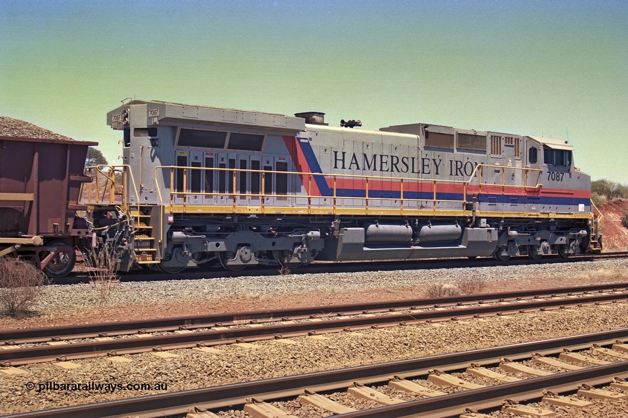 252-12
Cockatoo Siding 273 km on the Hamersley Iron line to Yandi, General Electric built 9-44CW unit 7087 with serial number 47766 from the original 1994 build idles away on the western end of the ballast train as it is loaded and slowly progresses into the back track siding Ballast plough BP 01 is behind the locomotive. Location is roughly [url=https://goo.gl/maps/rNdCHRcDhbQuHTjd7]here[/url]. 24th November 2001.
Keywords: 7087;GE;Dash-9-44CW;47766;