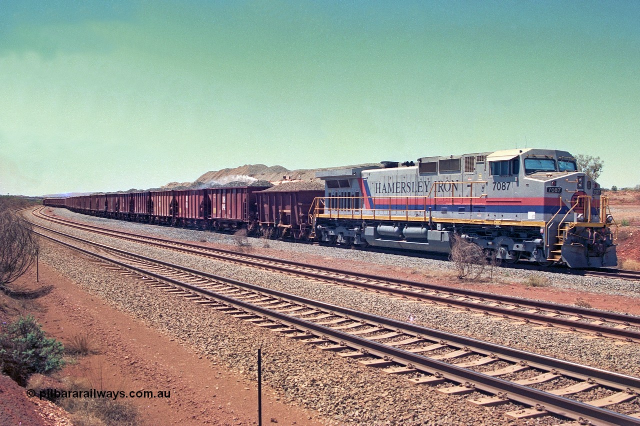 252-14
Cockatoo Siding 273 km on the Hamersley Iron line to Yandi, General Electric built 9-44CW unit 7087 with serial number 47766 from the original 1994 build idles away on the western end of the ballast train as it is loaded and slowly progresses into the back track siding Ballast plough BP 01 is behind the locomotive. Location is roughly [url=https://goo.gl/maps/rNdCHRcDhbQuHTjd7]here[/url]. 24th November 2001.
Keywords: 7087;GE;Dash-9-44CW;47766;