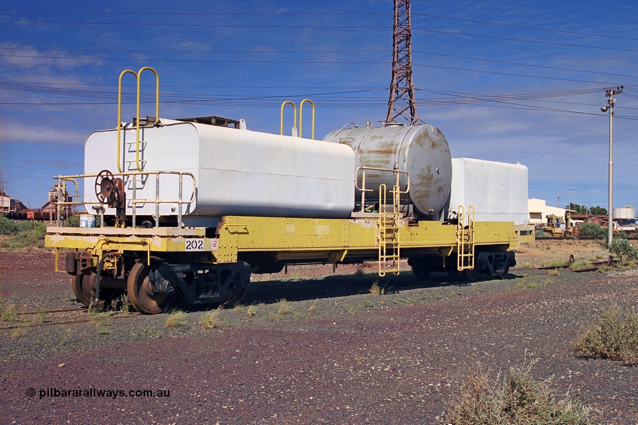 253-34
Nelson Point hard stand area, riveted flat waggon 202 with three water tanks fitted, view of handbrake end, originally part of the 'camp train', modified by Mt Newman Mining railway workshops.
Keywords: BHP-flat-waggon;
