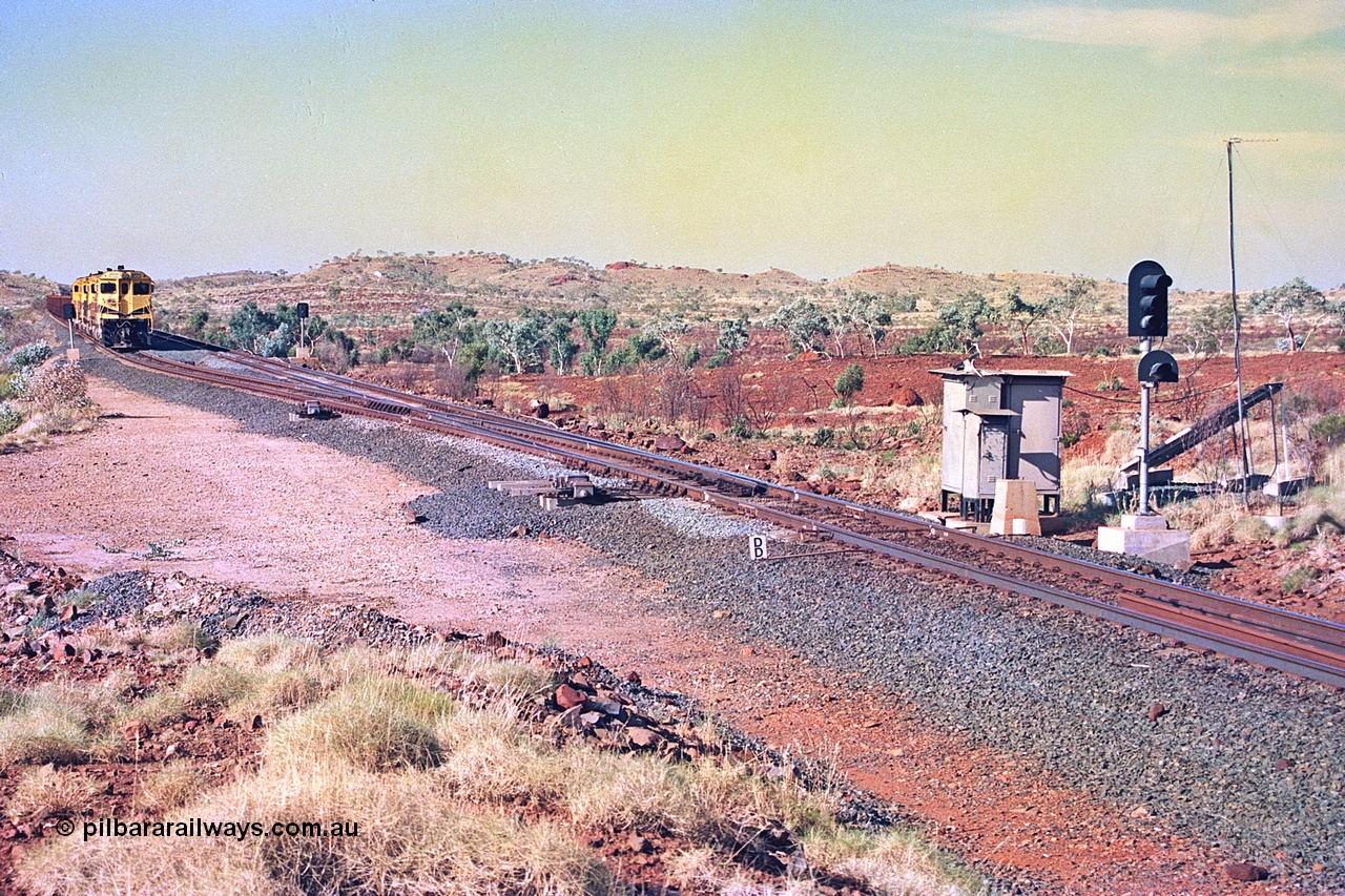 256-06
Maitland Siding located between the 92.8 and 95.1 km on the Cape Lambert line, view of the south end points and swing nose frog with dragging detector bars, solar panel and cabinets for signal and point control with an empty train sitting in the passing track awaiting a meet. May 2002.
