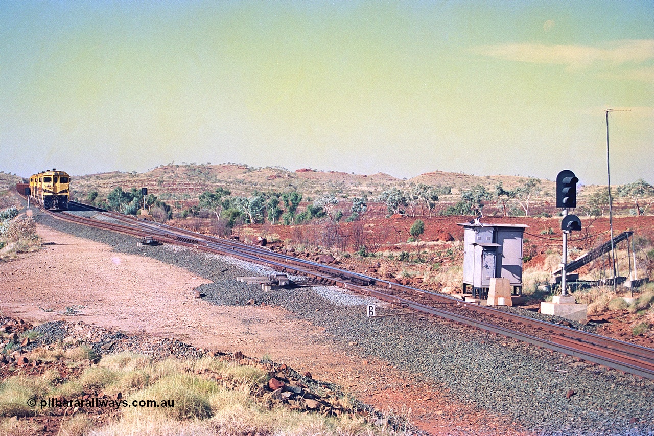256-07
Maitland Siding located between the 92.8 and 95.1 km on the Cape Lambert line, view of the south end points and swing nose frog with dragging detector bars, solar panel and cabinets for signal and point control with an empty train sitting in the passing track awaiting a meet. May 2002.
