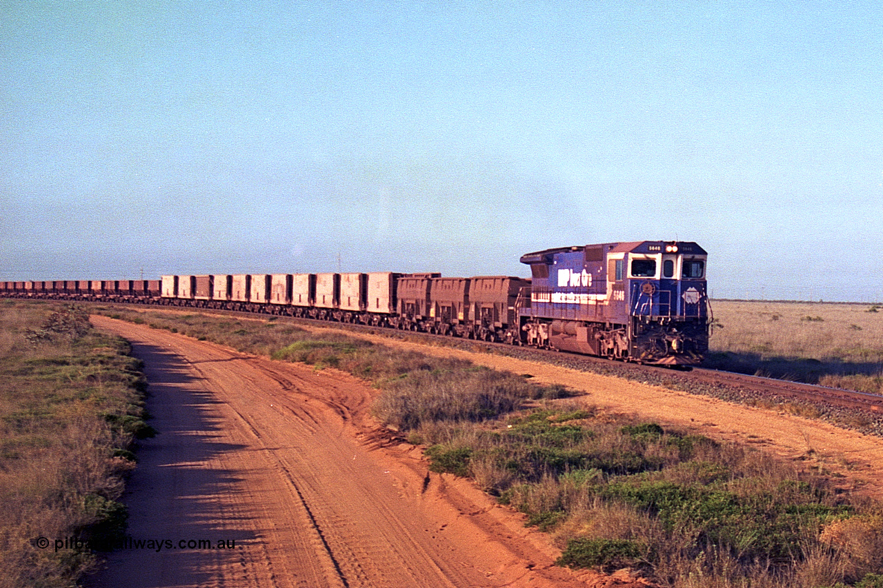 257-25
Goldsworthy Junction, an empty train runs between the junction and the Broome Rd crossing behind the standard single locomotive 5646 'White Springs', a Goninan 1992 built GE CM40-8 model with serial number 5244-11 / 92-135. The four styles of waggon in use are visible, behind the loco are three Golynx waggons, then a number of Gunderson USA builds, the ribbed type is a Portec USA built and then following are the Tomlinson WA and Scotts of Ipswich built 70 ton waggons. Late 2001.
Keywords: 5646;Goninan;GE;CM40-8;8244-11/92-135;