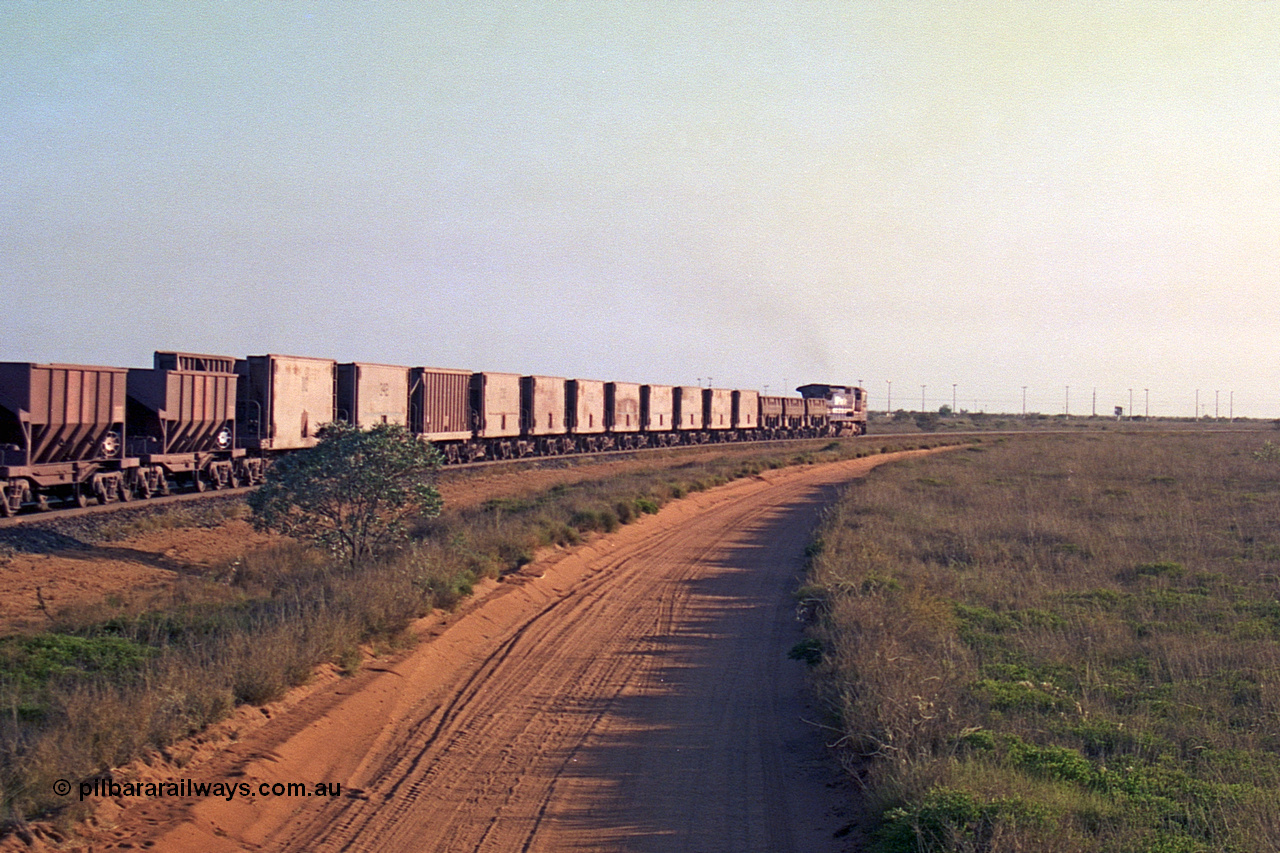257-27
Goldsworthy Junction, an empty train runs between the junction and the Broome Rd crossing behind the standard single locomotive 5646 'White Springs', a Goninan 1992 built GE CM40-8 model with serial number 5244-11 / 92-135. The four styles of waggon in use are visible, behind the loco are three Golynx waggons, then a number of Gunderson USA builds, the ribbed type is a Portec USA built and then following are the Tomlinson WA and Scotts of Ipswich built 70 ton waggons. Late 2001.
