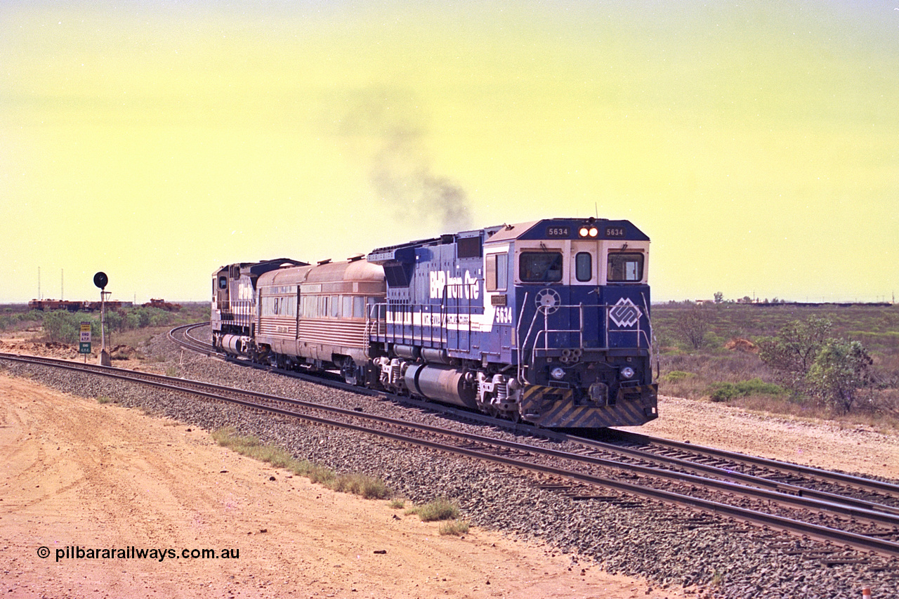 267-19
Goldsworthy Junction, CM40-8M GE unit 5634 'Boodarie' serial number 8151-07 / 91-120 leads the Sundowner Special on the Newman mainline leg of the Goldsworthy Junction and triangle, with the Sundowner coach in the middle and sister CM40-8M 5653 bringing up the rear.
This train, and the empty before it, were delayed due to a jamming switch for the transfer road where Tamper 2 and Ballast Regulator 31 are holding track. They can be seen behind the signal sitting on the transfer road. Friday 12th of April 2002.
Keywords: 5634;Goninan;GE;CM40-8M;8151-07/91-120;rebuild;AE-Goodwin;ALCo;C636;5457;G6027-1;