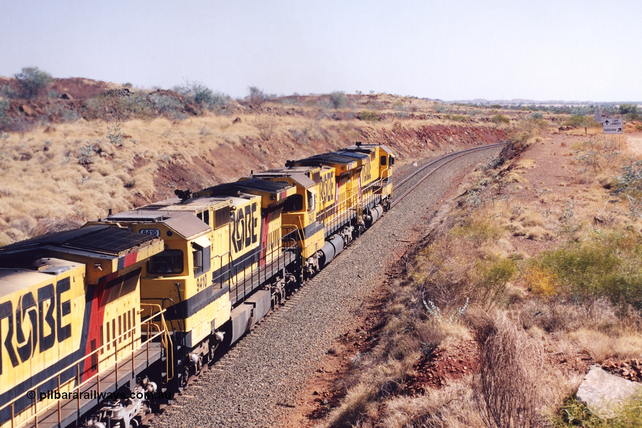 283-35
Near Woodbrook as quad Robe River CM40-8M units 9414, 9420, 9410 and 9525 work a loaded 202 waggons bound for Cape Lambert as they pass through the cutting at the 37.5 km pipe bridge. 9410 which is a Goninan WA ALCo to GE rebuild CM40-8M with serial 2160-03 / 96-202 from March 1996 riding on Dofasco bogies and was originally a Comeng NSW built M636 ALCo serial C-6096-5 and built new for Mt Newman Mining (later BHP Iron Ore) in November 1975 and numbered 5500. Everything below the frame is ALCo, with the Comeng build style flat fuel tank, while above is GE and Pilbara Cab. 22nd May 2002.
Keywords: 9410;Goninan;GE;CM40-8M;2160-03/96-202;rebuild;Comeng-NSW;ALCo;M636;C-6096-5;