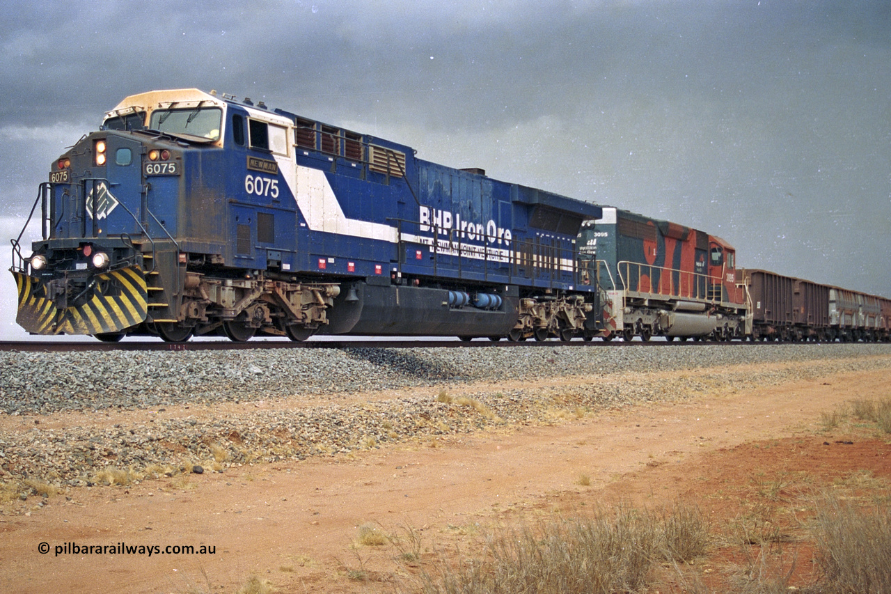 284-34
Bing Siding, 18 km south of Nelson Point and BHP's GE built AC6000 unit 6075 'Newman', serial number 51097, holds the mainline with a loaded train and EMD SD40R unit 3095 as second unit. Late 2004.
Keywords: 6075;GE;AC6000;51067;