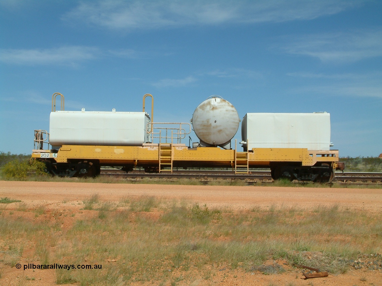 040419 102309
Abydos back track, riveted flat waggon 202 with three water tanks fitted, side view, shows access ladder profiles, originally part of the 'camp train', modified by Mt Newman Mining railway workshops.
Keywords: BHP-flat-waggon;