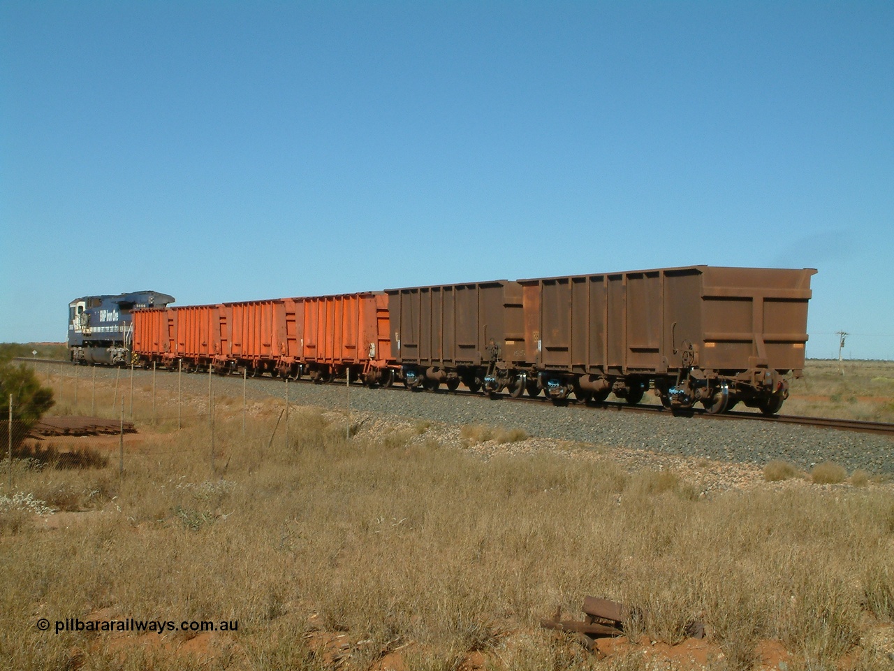 040806 091122
Goldsworthy Junction, trailing view of the weighbridge test train with the four orange weighbridge test waggons and one of the two Comeng built ore waggons to provide braking, 5666 is the power.
