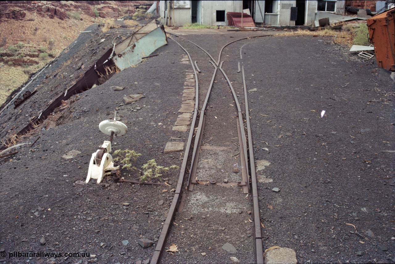 194-06
Wittenoom Gorge, Colonial Mine, asbestos mining remains, view looking south, set of points with cheese knob lever, the right track leads to the mine adit which can just be made out on the far right corner, the track on the left is the 'dump road' with the chute for the waggon discharge to gravity feed down to the crusher building.
