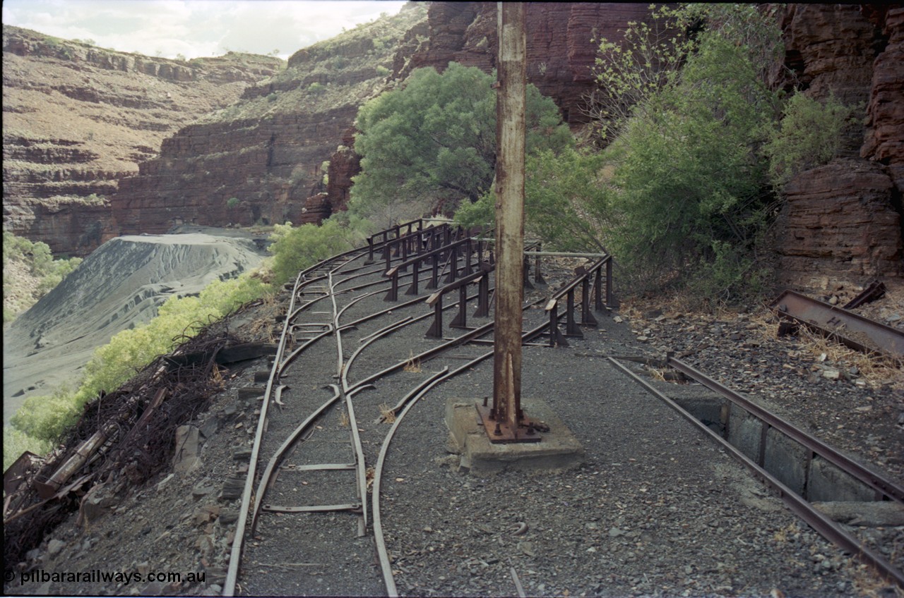 194-13
Wittenoom, Colonial Mine, asbestos mining remains, railway workshops with 4 loco storage roads and an inspection pit, the raised ramps are for removing the battery modules off the locomotives, looking south. Tailings in the background.
