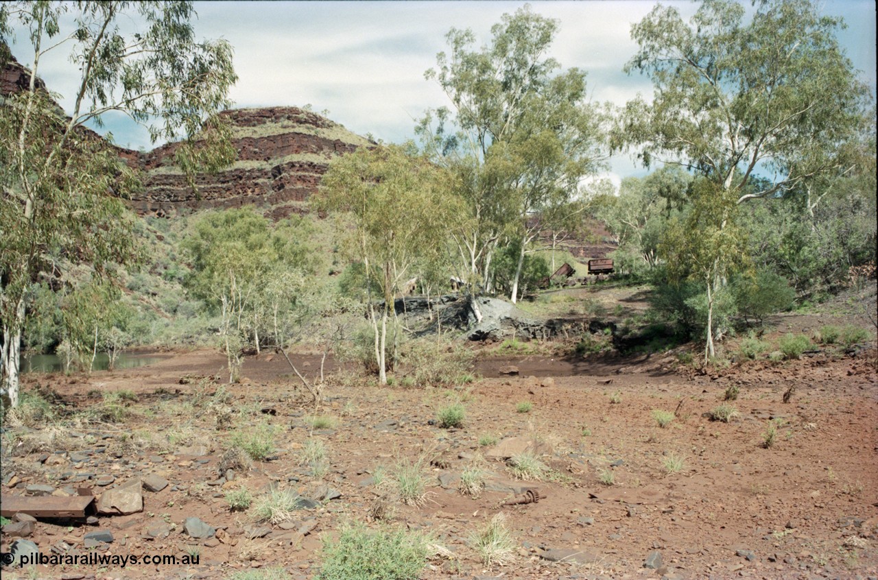 196-33
Wittenoom Gorge, Gorge Mine area, asbestos mining remains, view looking south up the gorge past the mill site of the river and tailings, ore waggons visible.
