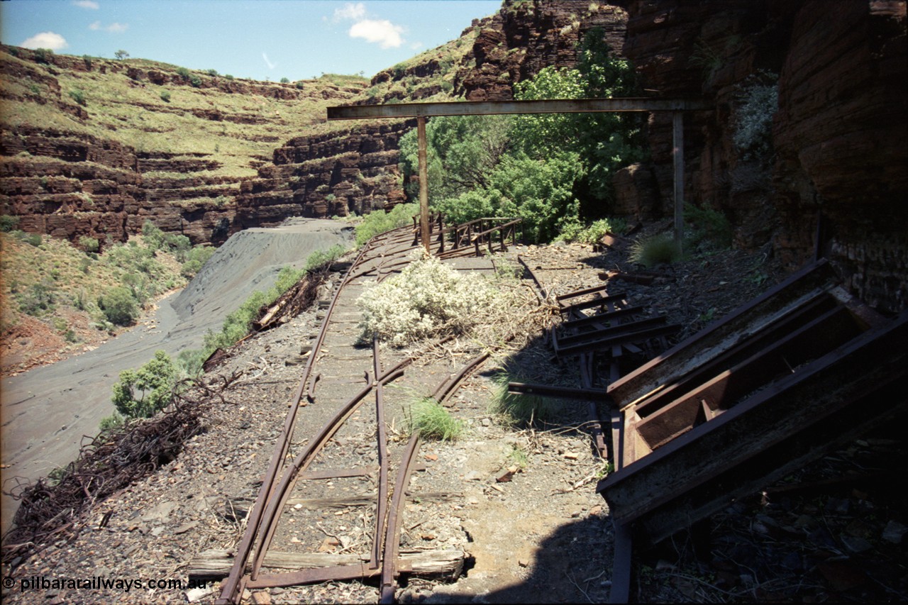 197-10
Wittenoom, Colonial Mine, asbestos mining remains, view looking south west of the open air service pit with gantry and locomotive storage roads with the battery off-take racks. The track used to continue around to the mine adits in the background.
