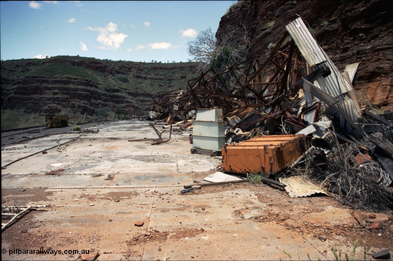 197-20
Wittenoom, Colonial Mine, asbestos mining remains, view of the demolished underground shift offices, upturned battery module, charging transformer, Mancha #4 battery locomotive on the right.
