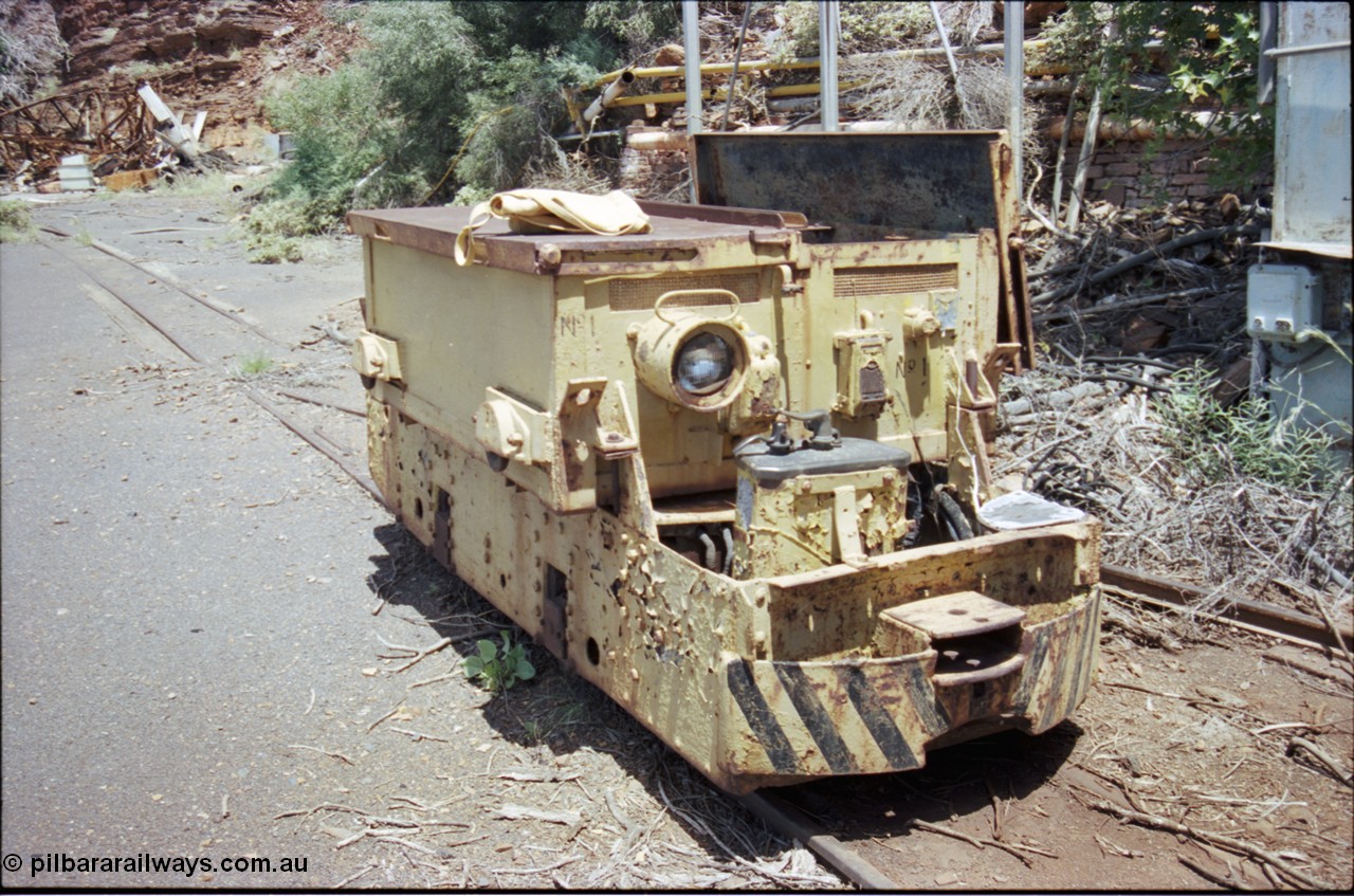 197-27
Wittenoom, Colonial Mine, battery module No.1, shows a slotted drop type hinge arrangement, headlight, English Electric hauler with Dick Kerr DB1 control stand, drivers position and coupling pocket, demolished underground offices and lamp room in the background
Keywords: Dick-Kerr;DB1;English-Electric;