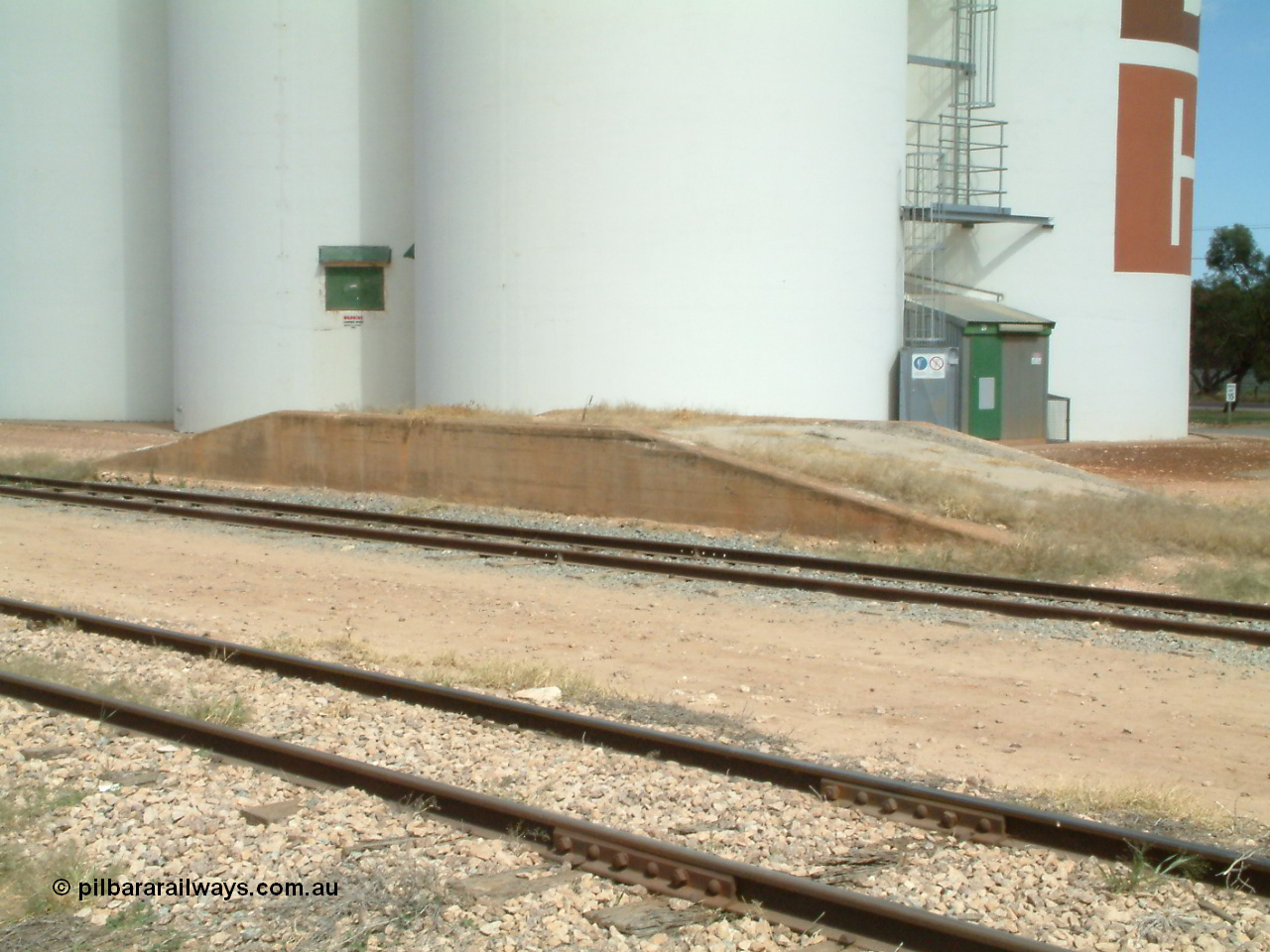 030405 133054
Wudinna, yard view across mainline and siding with loading ramp, SACBH silo complex behind, 5th April 2003.
