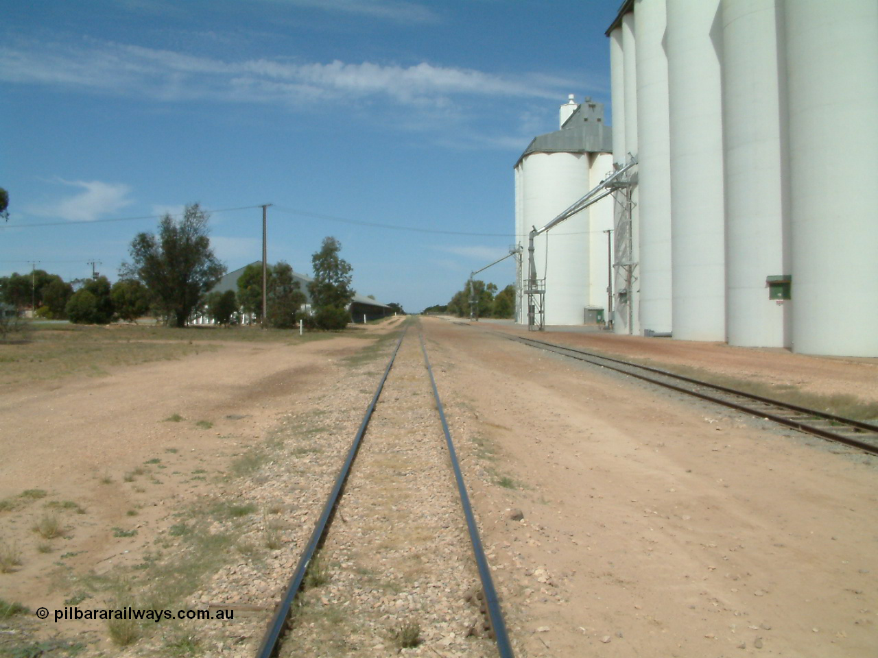 030405 133308
Wudinna, yard view looking along the mainline south with grain shed on the left and silo complexes and loading spouts on the right, old station site on the left, 5th April 2003.
