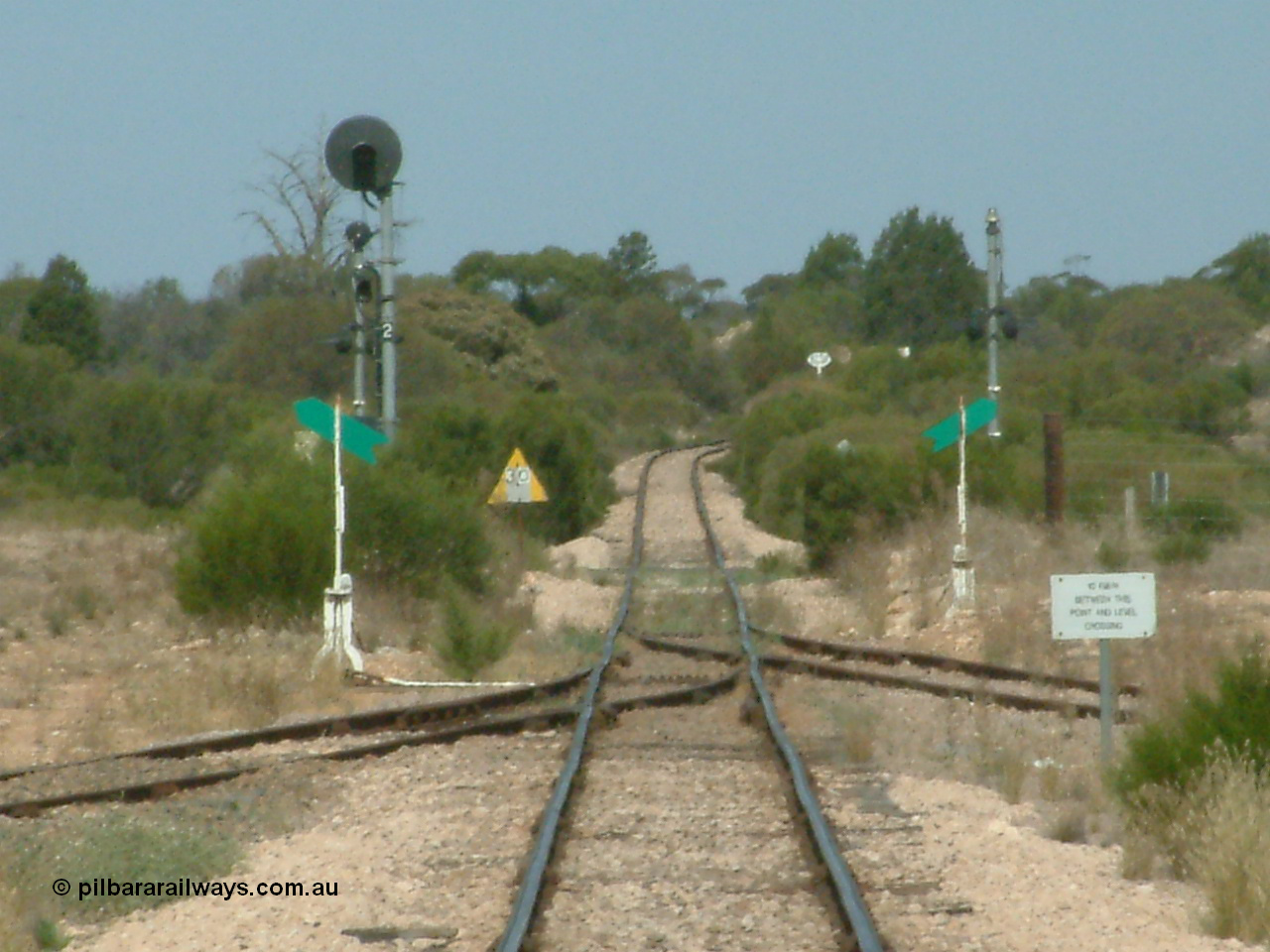030405 140546
Kyancutta, yard view looking south along the narrow gauge mainline with the siding point levers and indicators with the Eyre Highway grade crossing and one of only two electrically lit signals on the Eyre Peninsula Division. The cast iron 'Yard Limit' sign can be made out in the distance, 5th April 2003.
