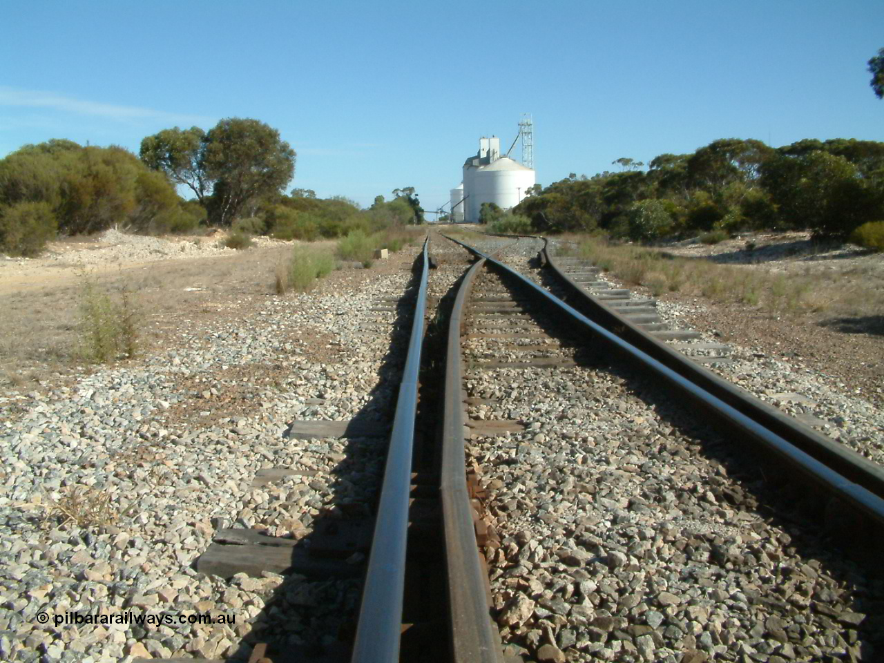 030405 154418
Lock, yard overview looking south from the northern end with a kink in the mainline with the points for the siding, silo complex visible in the background, 5th April 2003.
