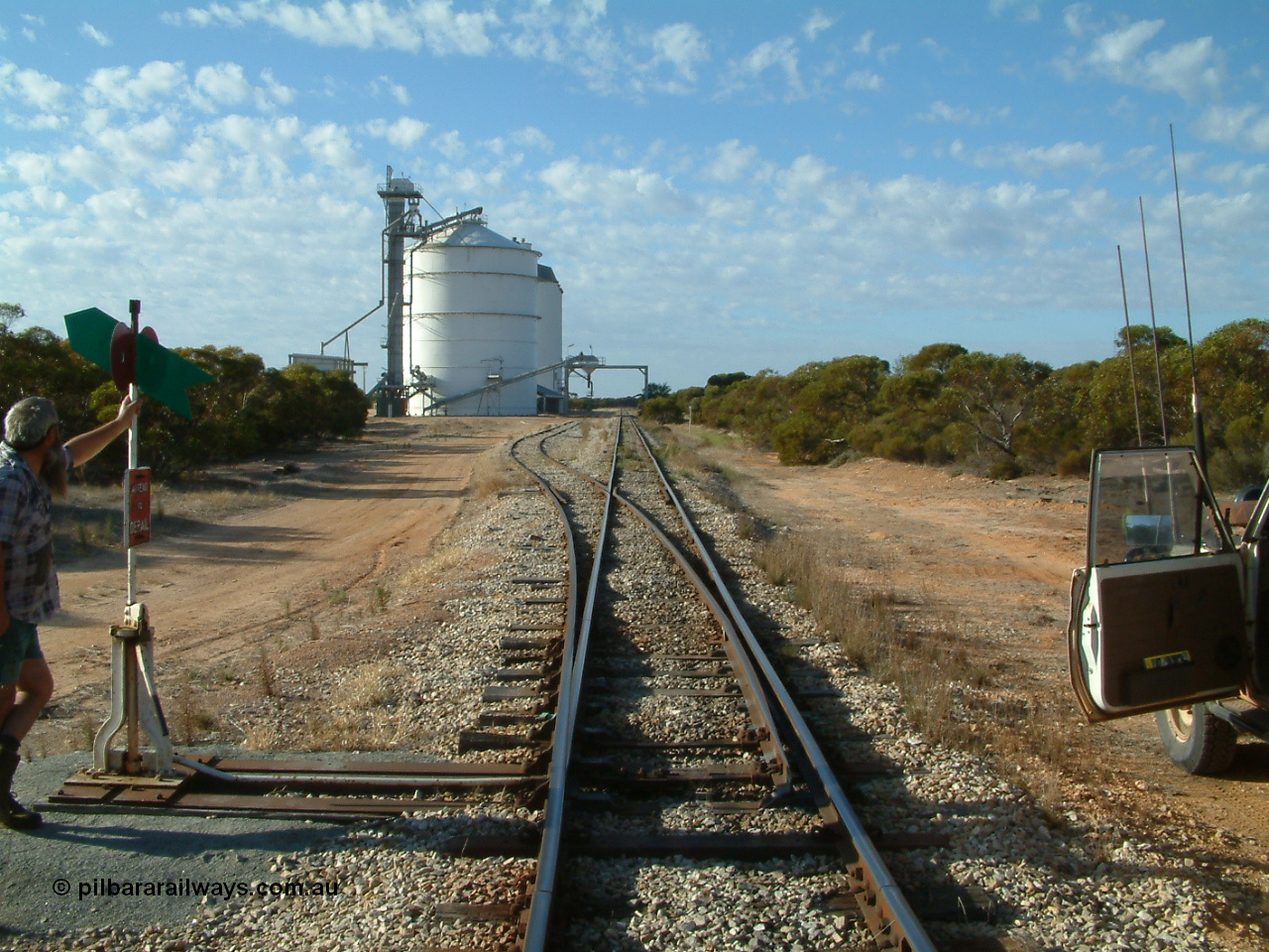 030406 082337
Murdinga, yard overview looking south down the mainline from the north end, points and point lever and indicator with Pope Searle, grain siding and silo complex with out-loading spout on gantry over both tracks. 6th April 2003.
