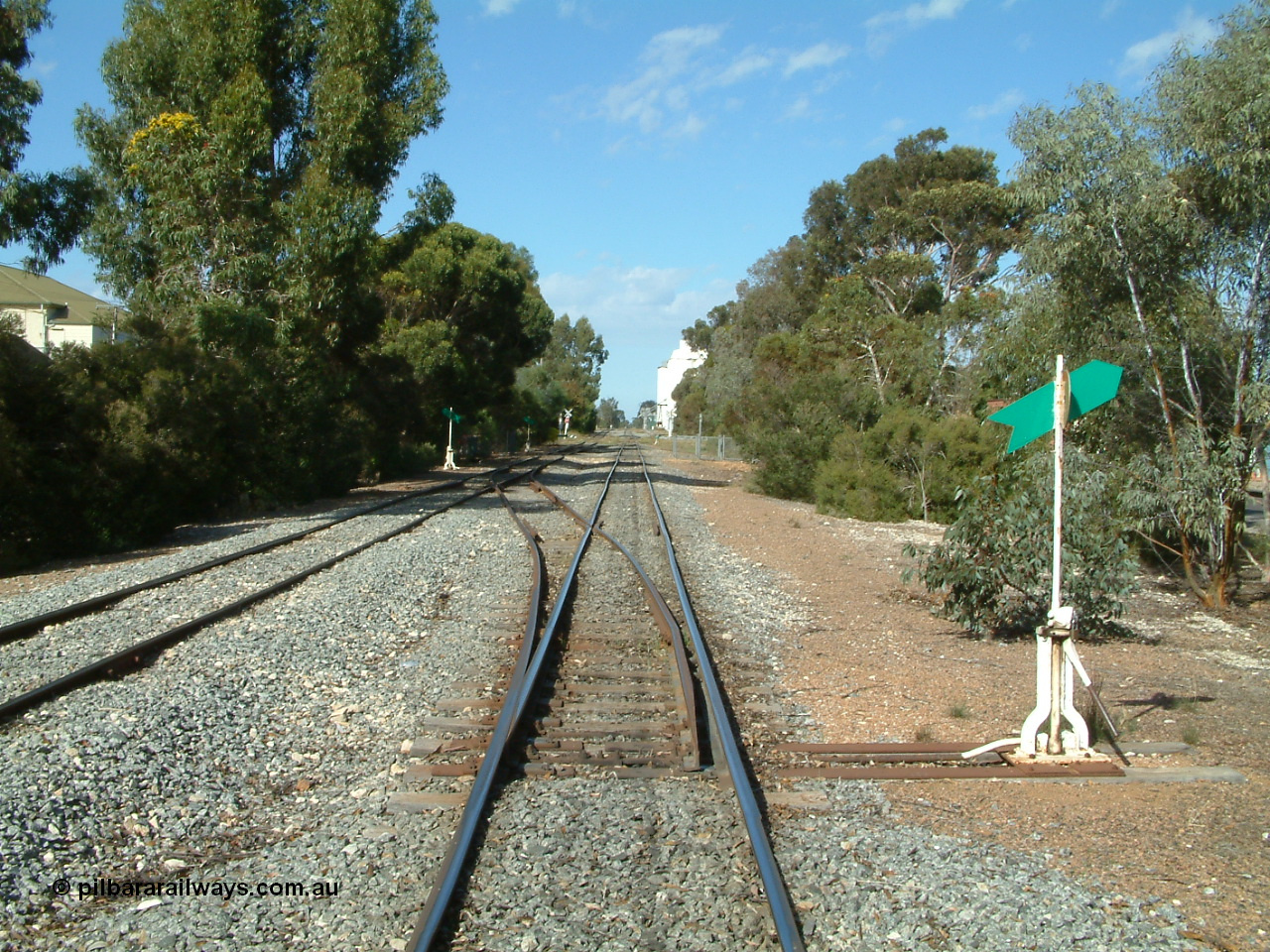 030406 094714
Cummins, yard overview looking south down the mainline from Thevenard with the line from Buckleboo coming in on the left, points, levers and indicators for the crossovers being visible with crib crossing and concrete silos in the distance. 6th April 2003.
