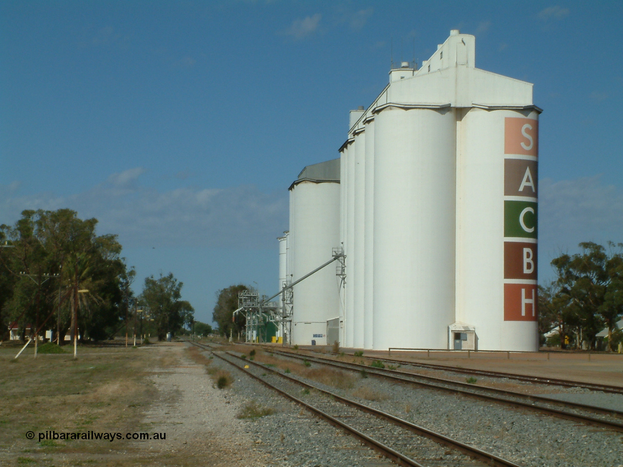030406 095408
Cummins, view of the three grain storage silo complexes, looking south along the old alignment for the fourth siding, and barracks at the left of frame. 6th April 2003.
