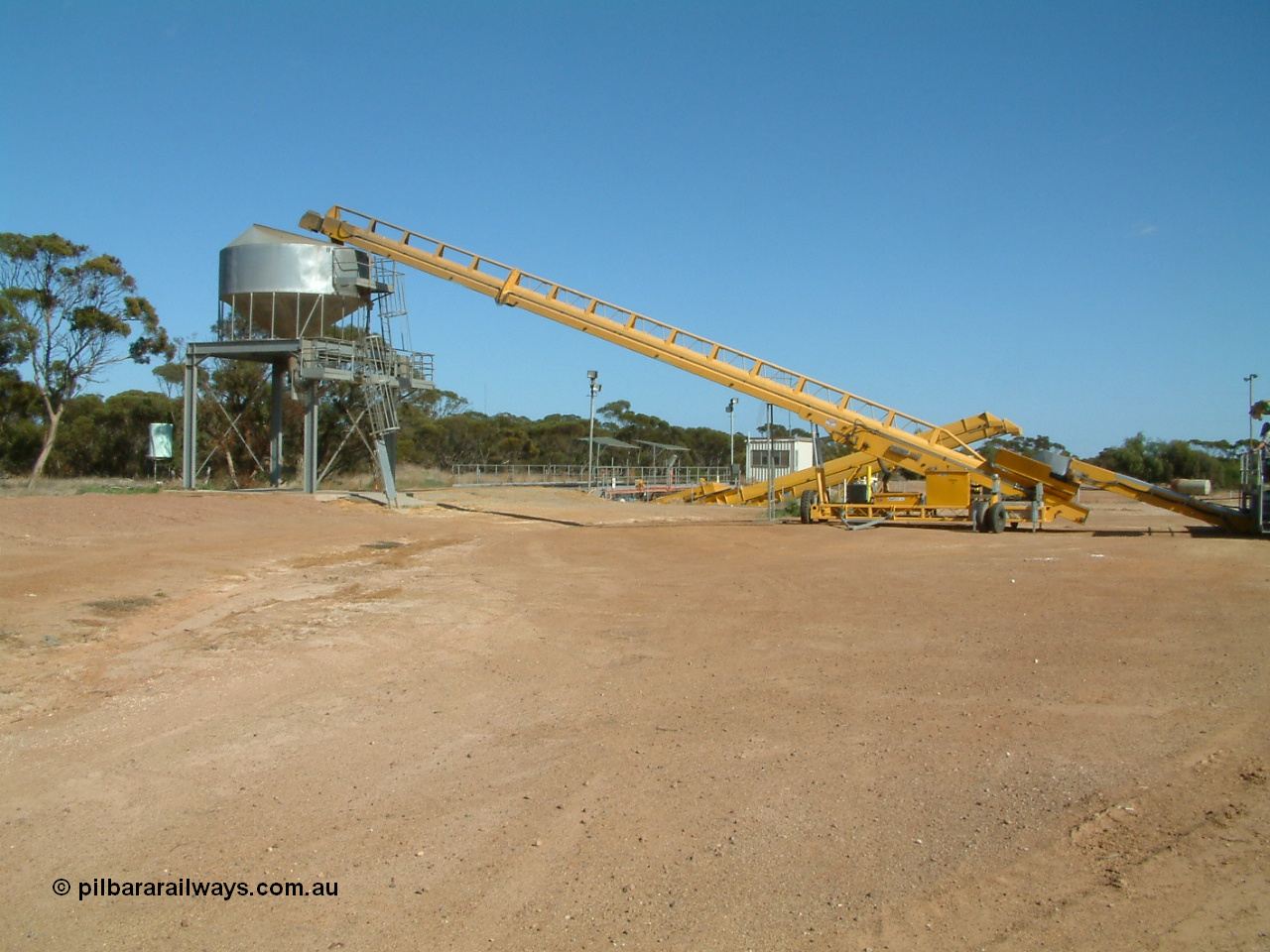 030406 100824
Cummins, expanded view of the grain bunker rail unloading facility with dual DOH 'Drive Over Hopper' and stackers for loading road vehicles and with the overhead outflow bin and feed conveyors for loading rail waggons. 6th April 2003.
