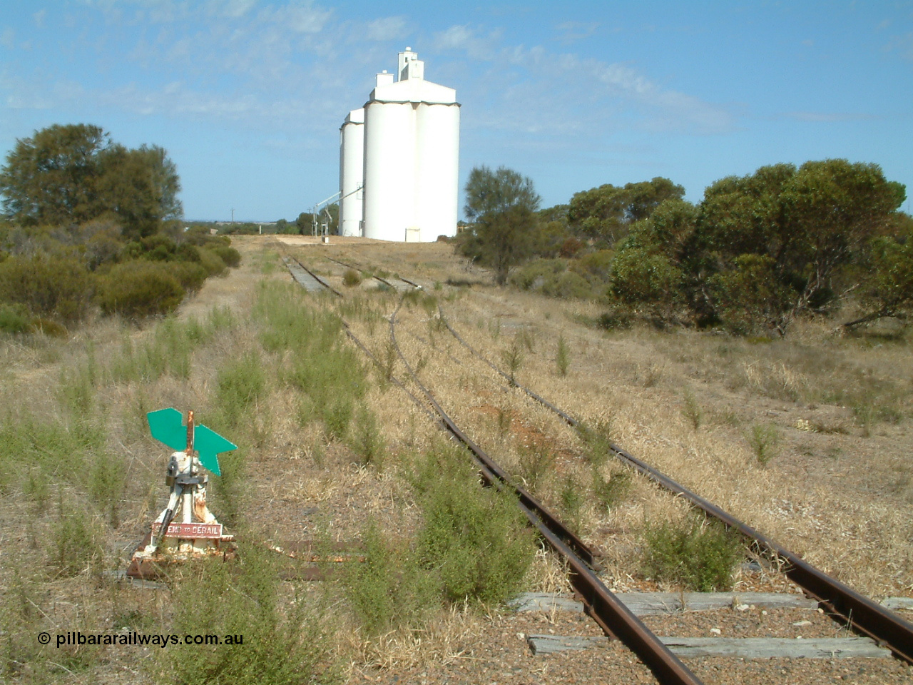 030406 141806
Kapinnie, station yard overview looking east towards Yeelanna, dwarf point lever and indicator, concrete silo complexes with outflow spouts. 6th April 2003.
