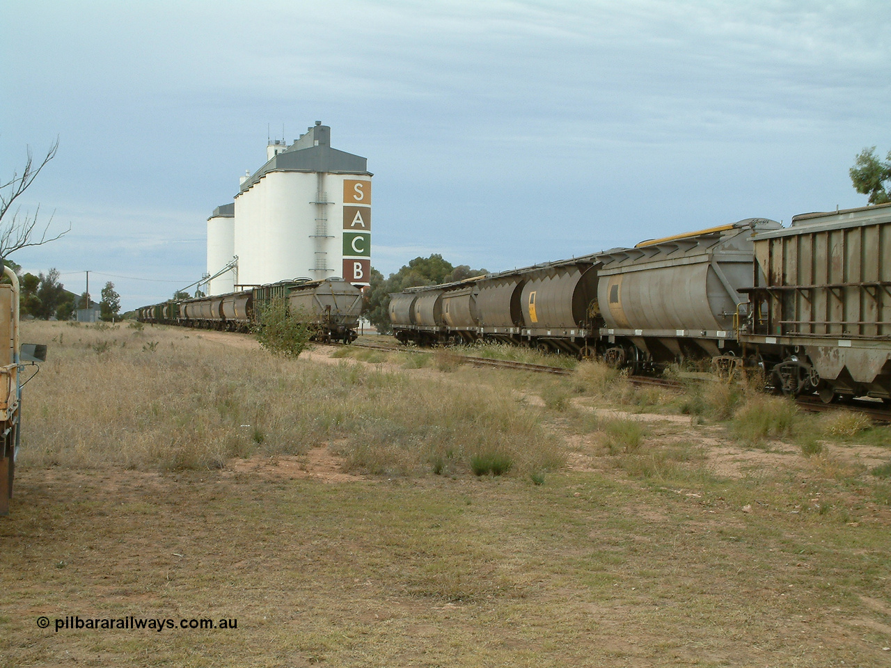 030407 082709
Wudinna, view looking south as the empty rake of bogie grain waggons is shunted into the siding for loading, showing HAN and HCN types of bogie grain hoppers. Concrete SACBH grain complex, horizontal grain bunker can be made out on the left. 7th April 2003.
Keywords: HAN-type;HCN-type;SAR-Islington-WS;Tulloch-Ltd-NSW;