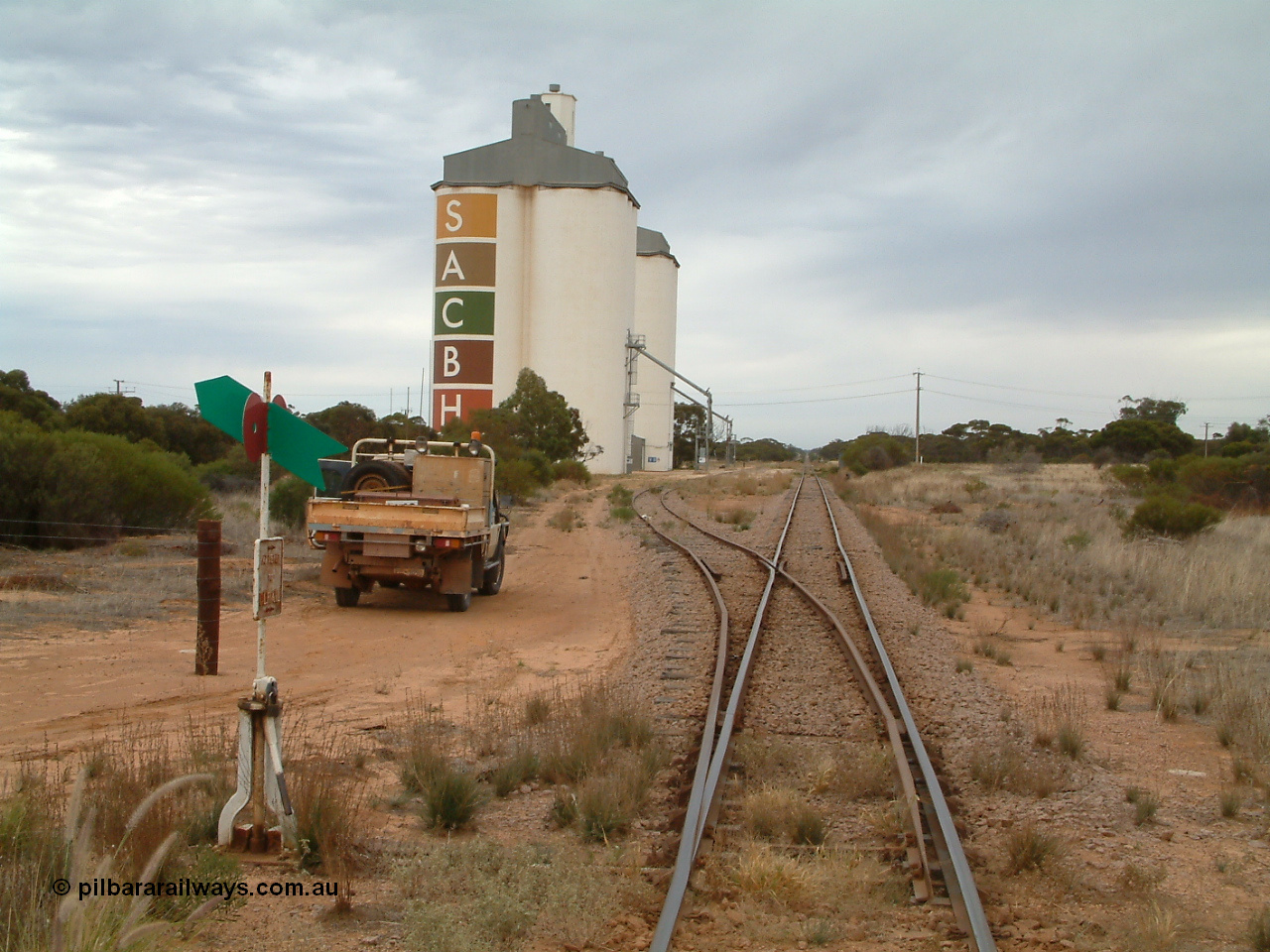 030407 085559
Yaninee, station yard overview looking north for the south end, concrete SACBH silo complexes, points, lever and indicator, mainline can be seen running straight into the distance. 7th April, 2003.
