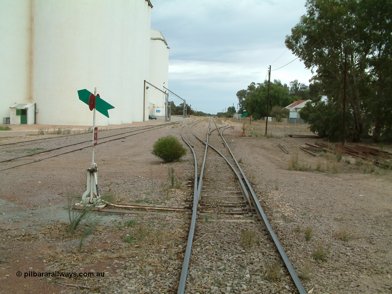 030407 094128
Minnipa, station yard overview looking north from the south end of yard down mainline, concrete silo complexes and out-flow spouts on the left with sidings running behind camera. Train control booth and shelter can be made out behind the second point lever - indicator. 7th April , 2003.
