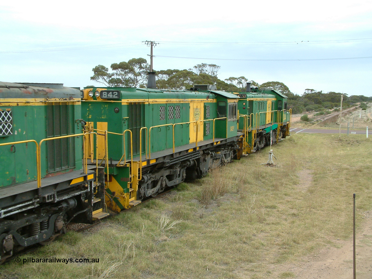 030407 100500
Minnipa, north bound empty grain train shunts across the grade crossing for Minnipa - Yardea Rd behind a trio of former Australian National Co-Co locomotives with rebuilt former AE Goodwin ALCo model DL531 830 class ex 839, serial no. 83730, rebuilt by Port Augusta Workshops to DA class, leading two AE Goodwin ALCo model DL531 830 class units 842, serial no. 84140 and 851 to shunt off empty waggons into the grain siding. 7th April, 2003.
Keywords: 830-class;842;AE-Goodwin;ALCo;DL531;84140;