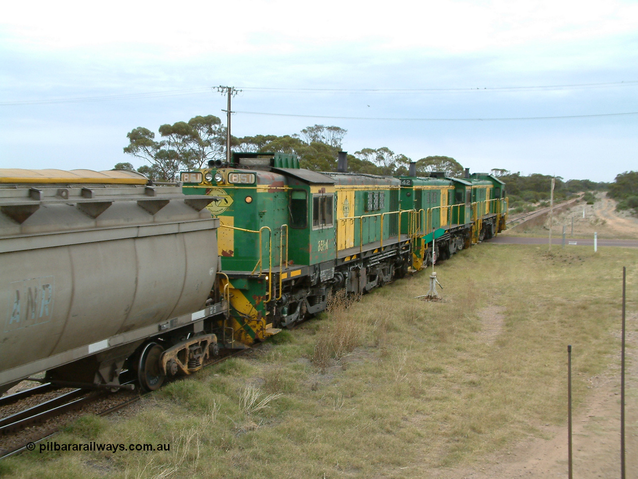 030407 100506
Minnipa, north bound empty grain train shunts across the grade crossing for Minnipa - Yardea Rd behind a trio of former Australian National Co-Co locomotives with rebuilt former AE Goodwin ALCo model DL531 830 class ex 839, serial no. 83730, rebuilt by Port Augusta Workshops to DA class, leading two AE Goodwin ALCo model DL531 830 class units 842, serial no. 84140 and 851 serial no. 84137, 851 having been on the Eyre Peninsula since delivered in 1962, to shunt off empty waggons into the grain siding. 7th April, 2003.
Keywords: 830-class;851;AE-Goodwin;ALCo;DL531;84137;