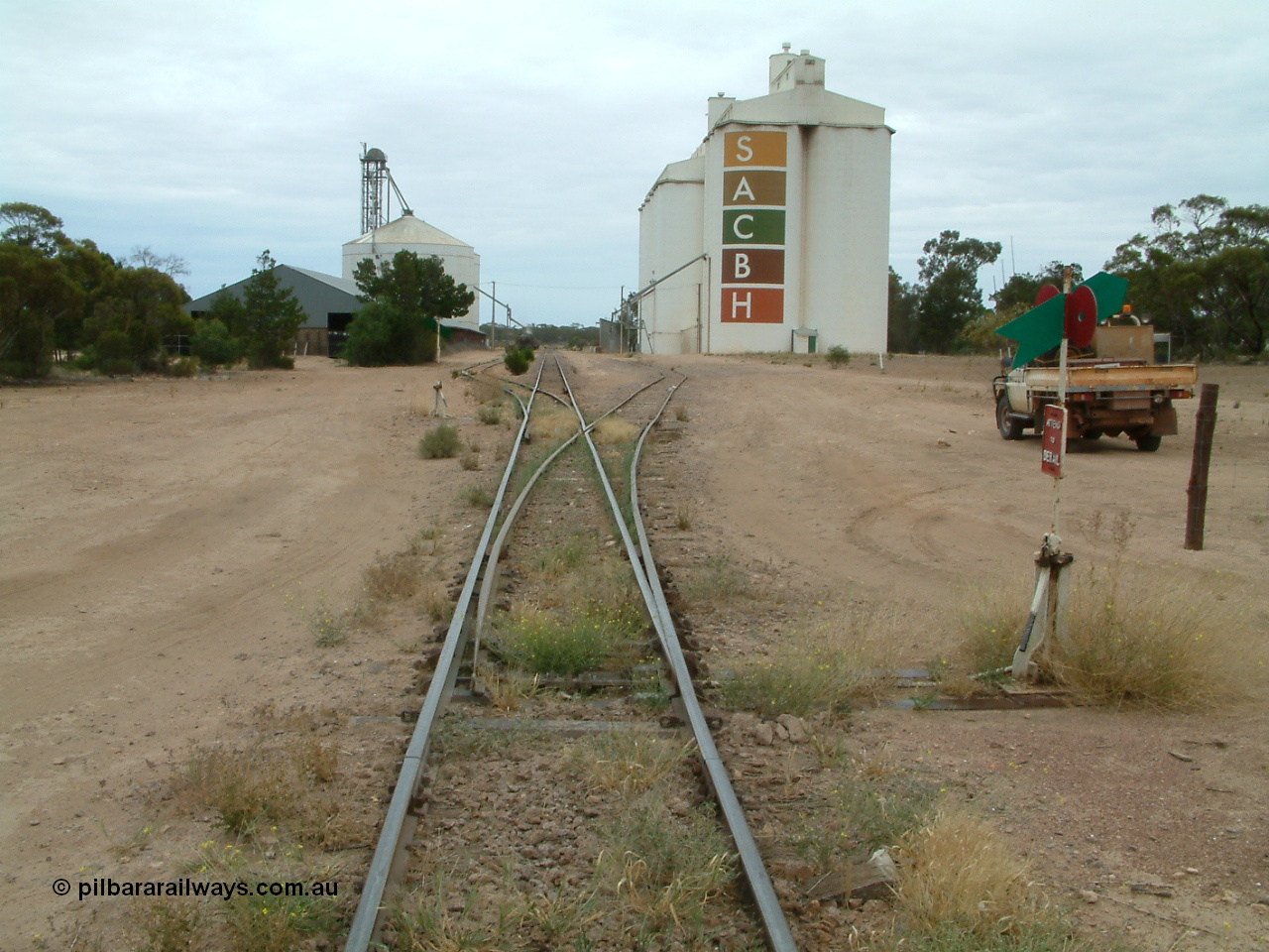 030407 104644
Poochera, station yard overview looking north from south end of yard, point levers and indicators for sidings, on the left is the horizontal grain shed with an Ascom style silo complex behind it, on the right the goods shed can be made out along with the SACBH concrete silo complexes. 7th April 2003.
