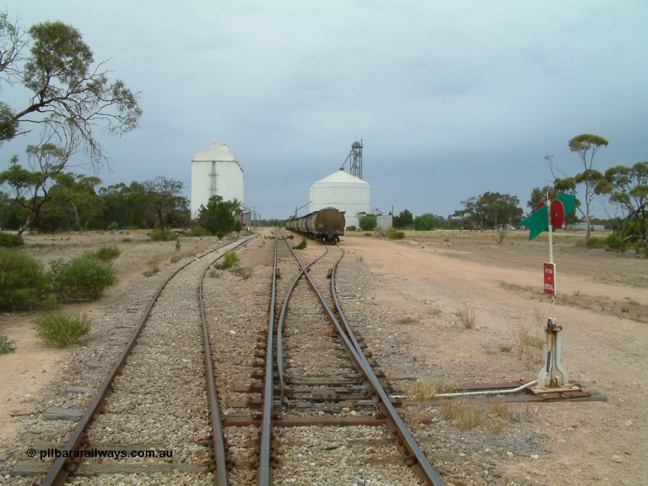 030407 105354
Poochera, yard overview looking south from the north end grain siding points, crane and goods shed just visible on the left of the goods siding, loaded grain rake on the grain siding with the Ascom silo complex to the right of the waggons. 7th April 2003.
