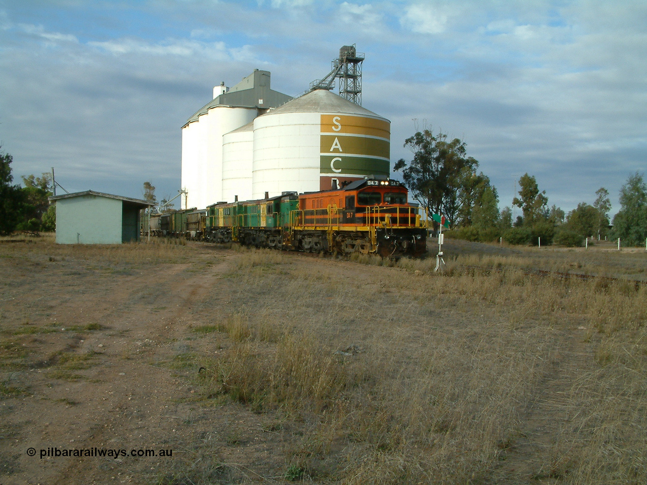 030409 080101
Warramboo, empty grain train arrives just after 0800 and stops for a crew change. Rebuild unit DA 7 in Australian Southern orange and black livery leads a pair of AE Goodwin built ALCo model DL531 830 class units 872 and 871 framed between the station building and the SACBH concrete silo complex.
Keywords: DA-class;DA7;83713;Port-Augusta-WS;ALCo;DL531G/1;48-class;4813;rebuild;