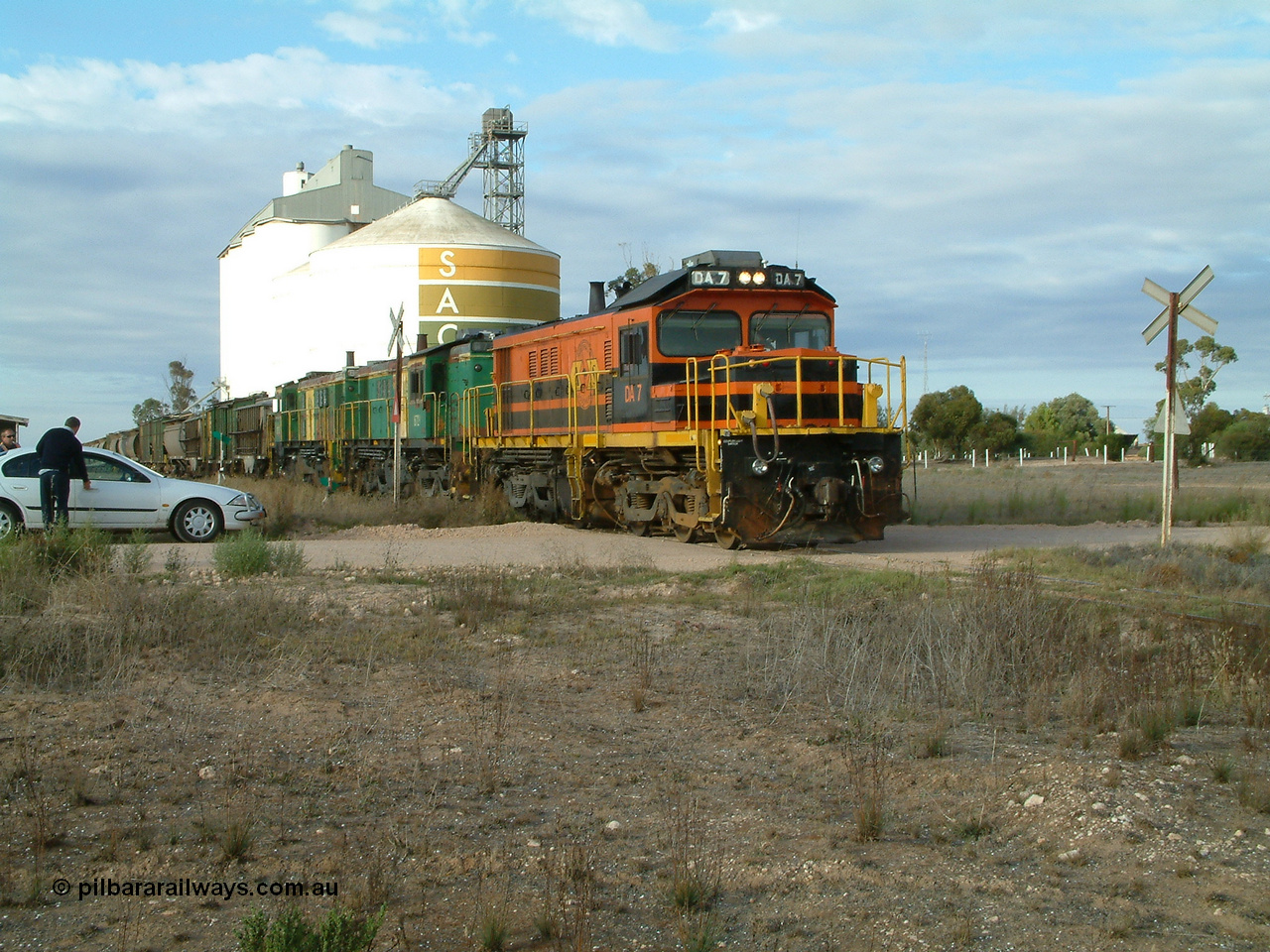 030409 080651
Warramboo, empty grain prepares to get underway following a crew change. Rebuild unit DA 7 in Australian Southern orange and black livery leads a pair of AE Goodwin built ALCo model DL531 830 class units 872 and 871, the relieved crew get in their car with the SACBH concrete silo complex behind.
Keywords: DA-class;DA7;83713;Port-Augusta-WS;ALCo;DL531G/1;48-class;4813;rebuild;