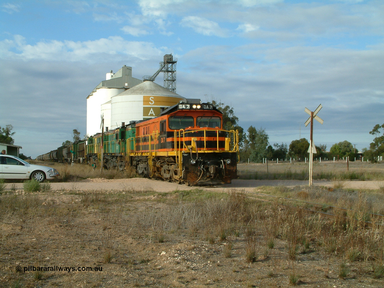 030409 080705
Warramboo, empty grain prepares to get underway following a crew change. Rebuild unit DA 7 in Australian Southern orange and black livery leads a pair of AE Goodwin built ALCo model DL531 830 class units 872 and 871, the long disused station building at left and the SACBH concrete silo complex behind.
Keywords: DA-class;DA7;83713;Port-Augusta-WS;ALCo;DL531G/1;48-class;4813;rebuild;