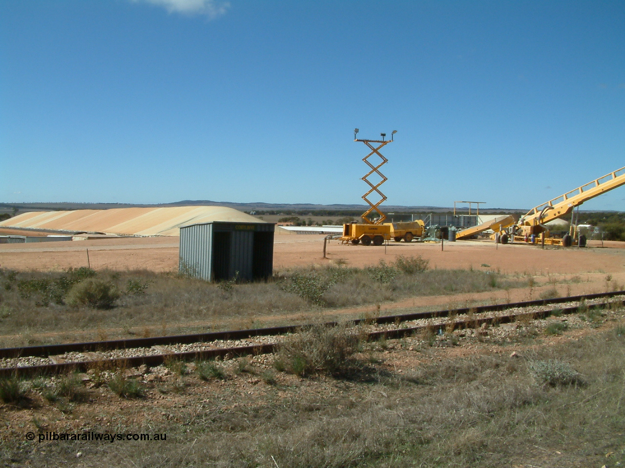 030411 105119
Kimba Grain Bunker site, overview of arrangement. Former Cortlinye shelter placed for crew, lighting tower for night time operation and the yellow auger goes to the over rail loadout bin.
