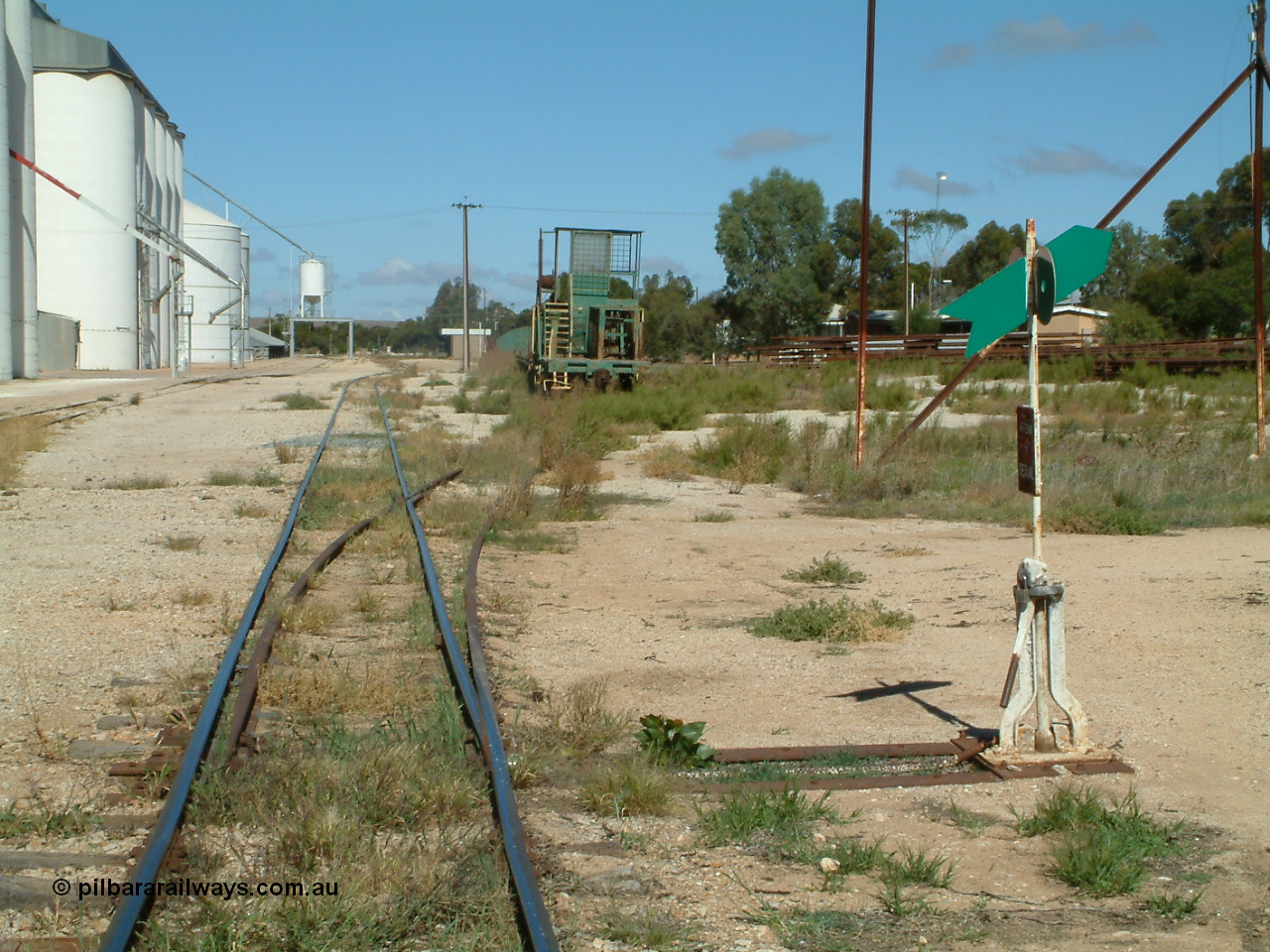 030411 105828
Kimba, station yard, view of rail transport set in the loading road, winch waggon, dumbbell point indicator. Barracks visible behind indicator, station building in the distance.
