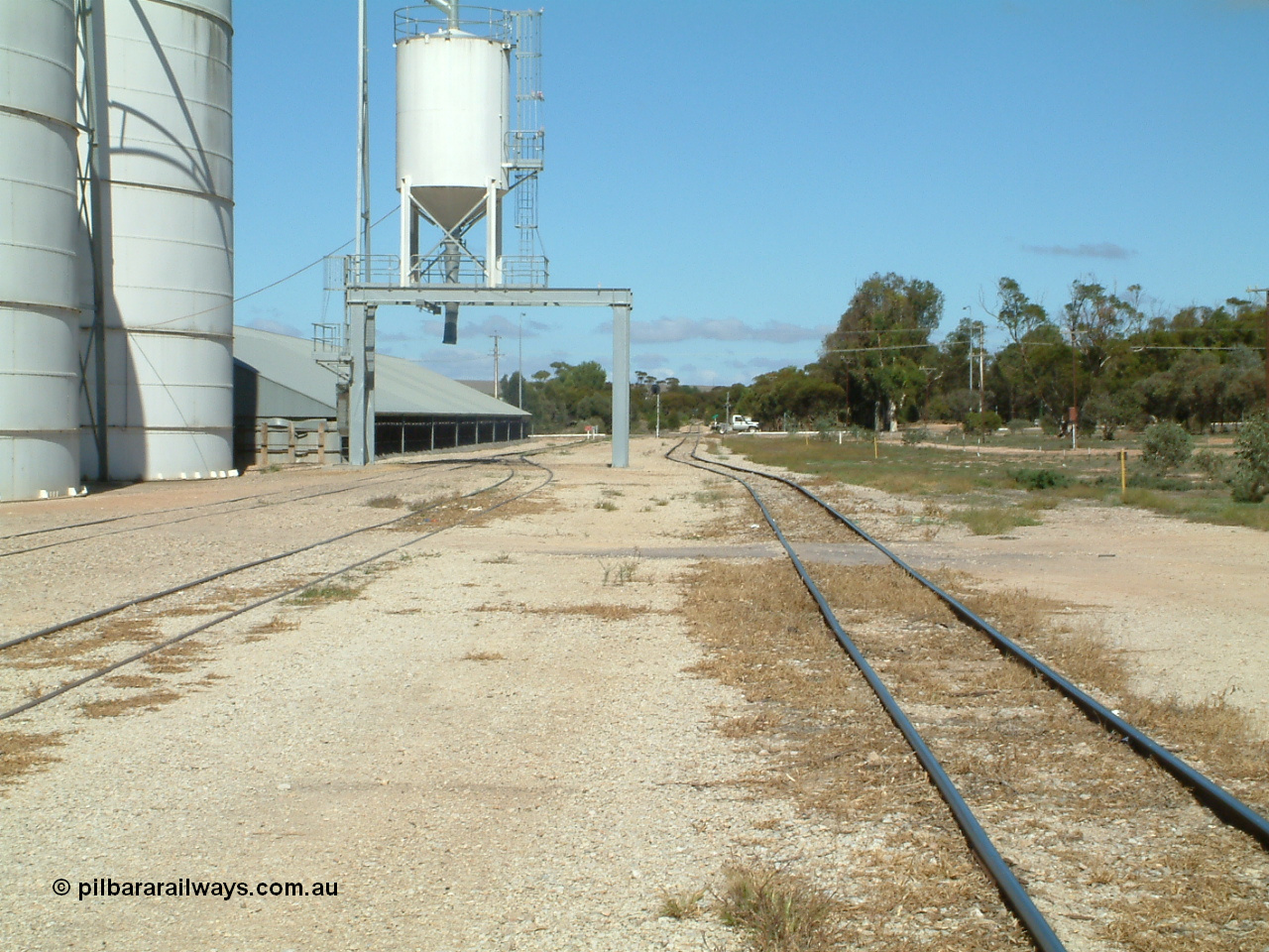 030411 110554
Kimba, yard view looking south, mainline on the right, Ascom loadout gantry and silo with horizontal bunker beyond that. Eyre Highway grade crossing in the distance.
