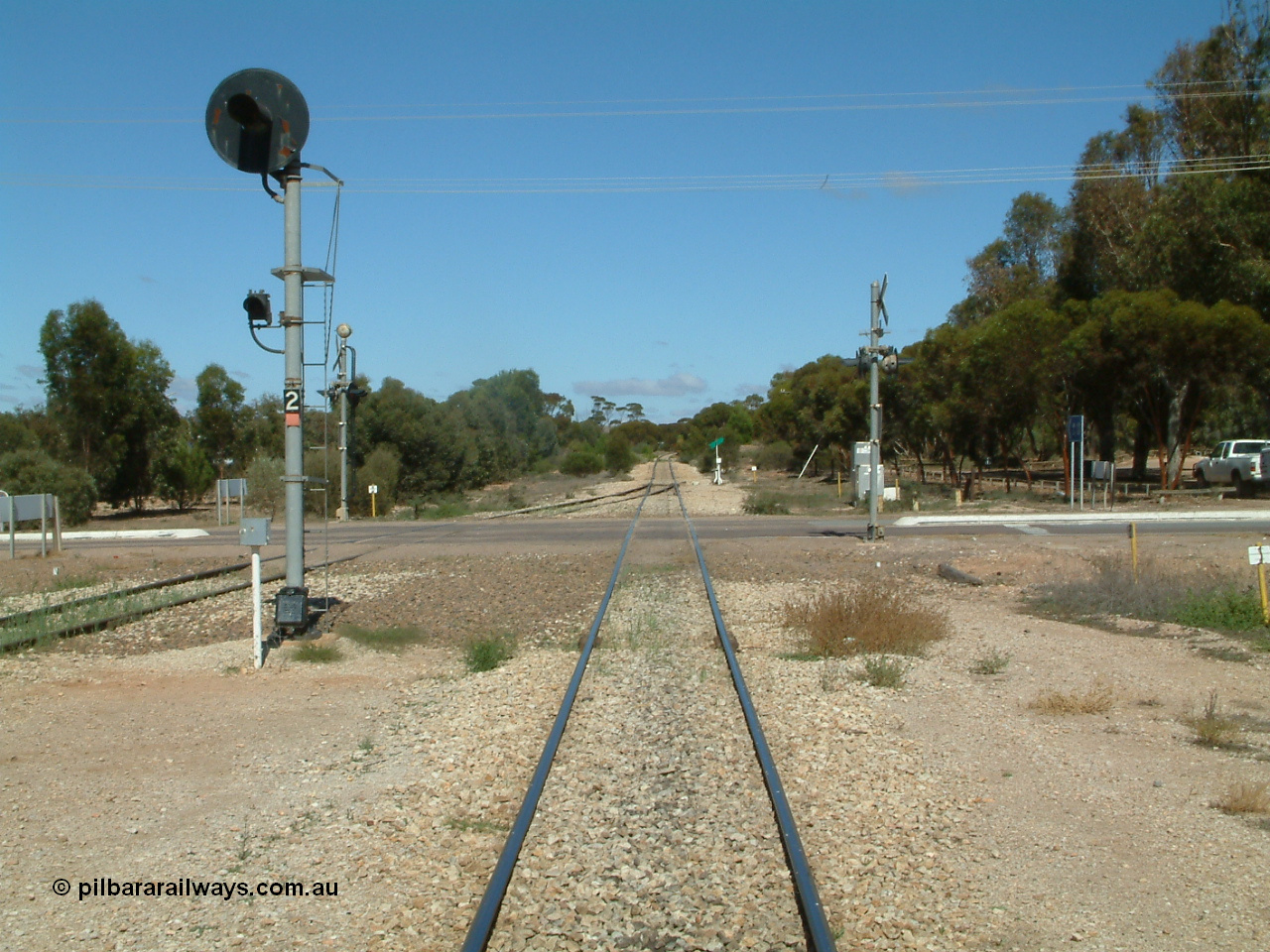 030411 110823
Kimba, looking south across the Eyre Highway grade crossing, the mainline has a coloured light signal, one of only three such signals on the Eyre Peninsula system, the others being at Kyancutta and Port Lincoln.
