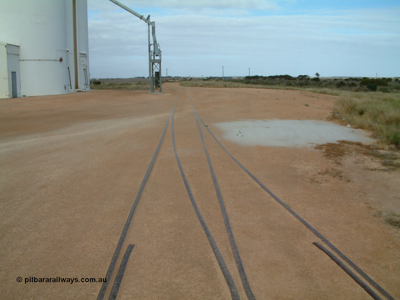 030414 154120
Penong, yard view looking east along the grain loop with concrete silo block 2 on the left and the crossover from the main to the loop coming in from the right. Station shelter is in the distance on the right.
