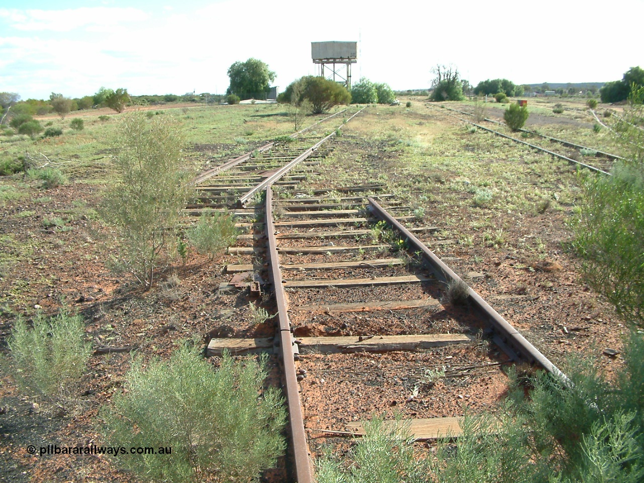 030415 155213
Tarcoola, at the 504.5 km, looking west, end of No. 1 Water Road running straight, removed points, No. 2 Loco, then No. 1 Loco and the points for the Camp Train Roads just visible on the right. Tank on stand and underground covered tank can be made out. [url=https://goo.gl/maps/y17pUsTYVeRwPsa67]GeoData location[/url]. 15th April 2003.
