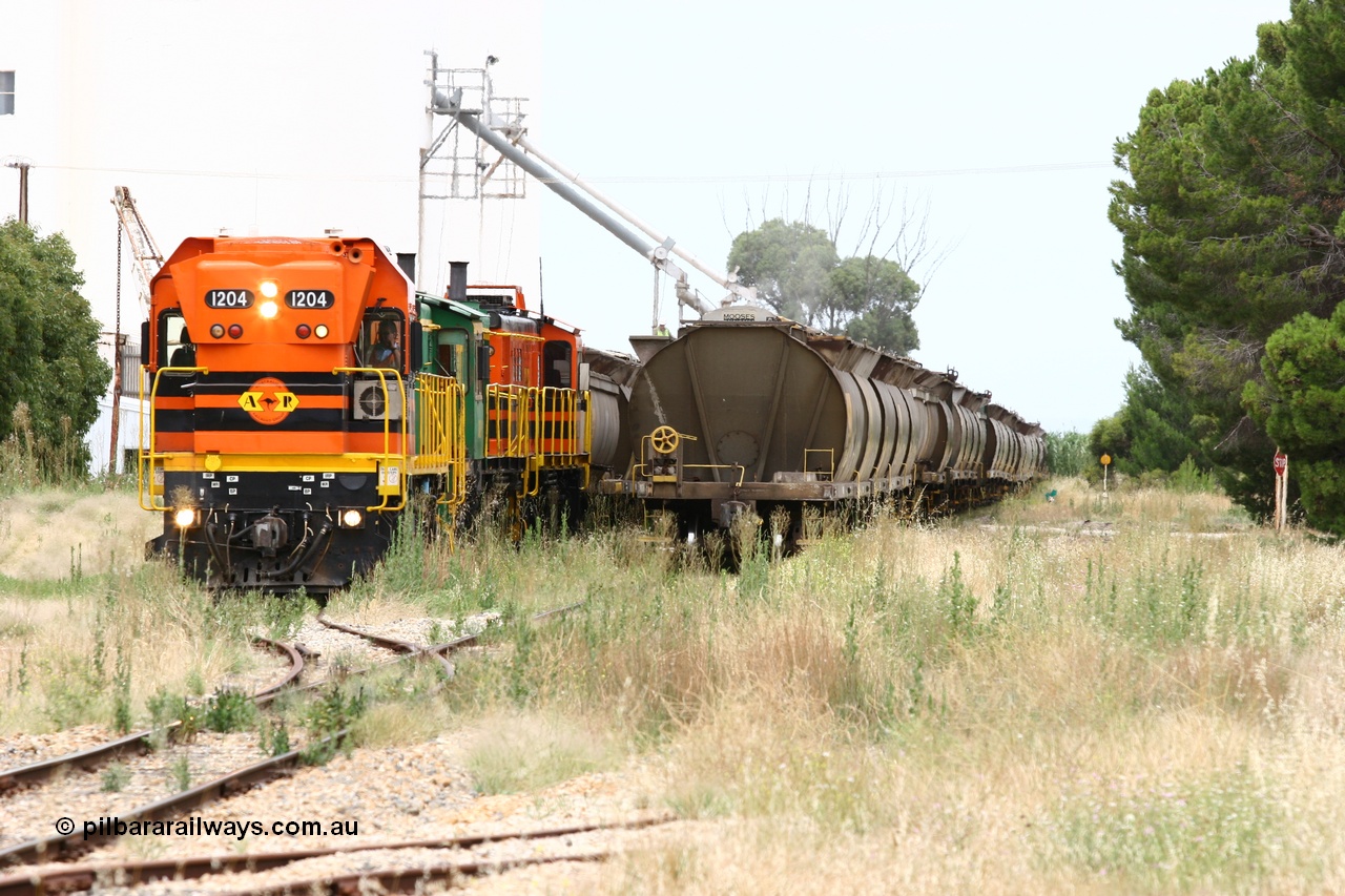 060110 2203
Yeelanna, overview as ARG 1200 class unit 1204, a Clyde Engineering EMD model G12C serial 65-428, originally built for the WAGR as the final unit of fourteen A class locomotives in 1965 and sent to the Eyre Peninsula in July 2004 stands with a rake of waggons into the grain siding with the 5 ton crane also visible as the locos are cut off with the remainder of the train holding the mainline. Off to the right is the former triangle. [url=https://goo.gl/maps/1JetzWBTGAw]Approx. location of image[/url].
Keywords: 1200-class;1204;Clyde-Engineering-Granville-NSW;EMD;G12C;65-428;A-class;A1514;