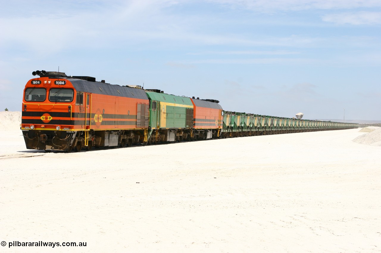 060113 2551
Kevin, standing on the mainline to Thevenard, and the train now identified as 6DD4 has commenced loading of gypsum but the 988 Cat front end loaders which takes about one and half hours to load. As the train reversed on the triangle the consist is the same heading back loaded with 1604 leading NJ 3 and 1601. 13th January 2006.
