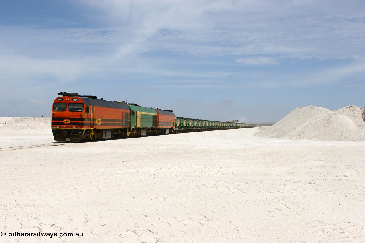 060113 2552
Kevin, standing on the mainline to Thevenard, and the train now identified as 6DD4 has commenced loading of gypsum but the 988 Cat front end loaders which takes about one and half hours to load. As the train reversed on the triangle the consist is the same heading back loaded with 1604 leading NJ 3 and 1601. 13th January 2006.
