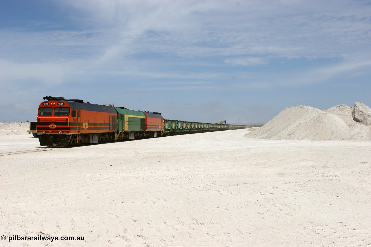 060113 2553
Kevin, standing on the mainline to Thevenard, and the train now identified as 6DD4 has commenced loading of gypsum but the 988 Cat front end loaders which takes about one and half hours to load. As the train reversed on the triangle the consist is the same heading back loaded with 1604 leading NJ 3 and 1601. 13th January 2006.
