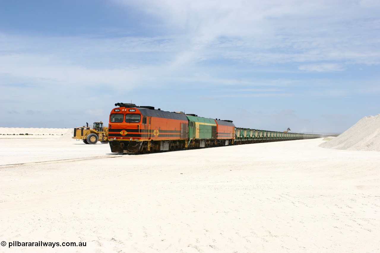 060113 2554
Kevin, narrow gauge locos 1604, NJ 3 and 1601 wait while their return working train 6DD4 is loaded on the mainline to Thevenard. The plant is behind the tipping loader and Kevin back around to the right behind the gypsum pile. 13th January 2006.
