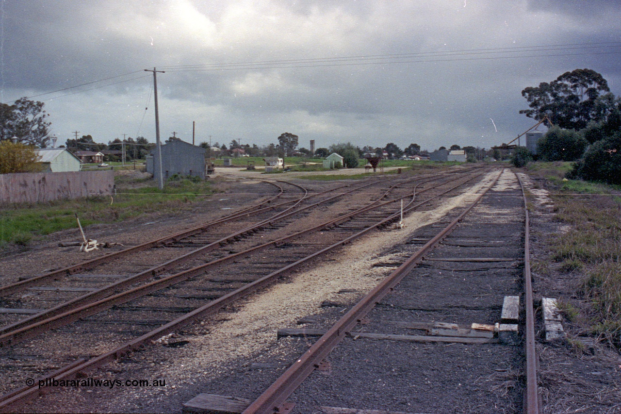 103-17
Wahgunyah station yard overview, super phosphate sheds on the left track, portable station building in middle of frame, silos in distance, scotch block and point levers in foreground.
